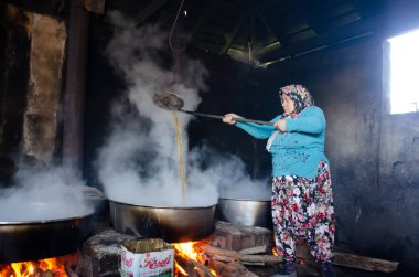 Kadınlar büyük kazanlarda pekmez pişiriyor, karanlık oda duman içinde.