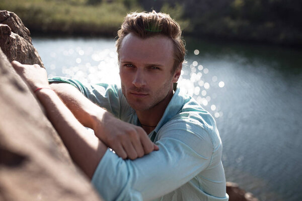 young attractive guy on the ocean meets sunset. The concept of fashion style on vacation