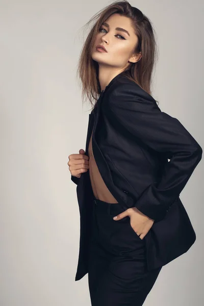 Fashion minimalist portrait of brunette female model on grey background. stylish clothing, black  classic style concept
