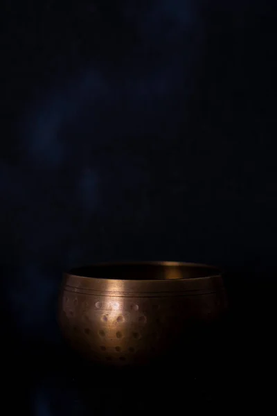 golden tibetan bowl with black background and smoke