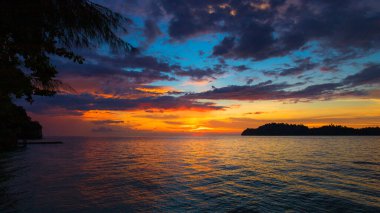 Sahilde gün batımında, arkada ada var.