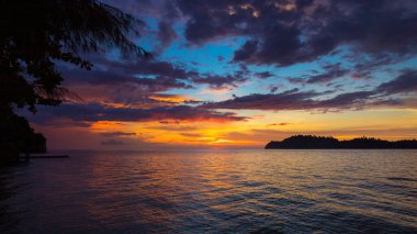Sahilde gün batımında, arkada ada var.