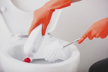 Yakın çekim. Klozet Fırçası kullanarak Temizleme turuncu lastik eldiven kadın elinde. Tuvalet yıkamak.