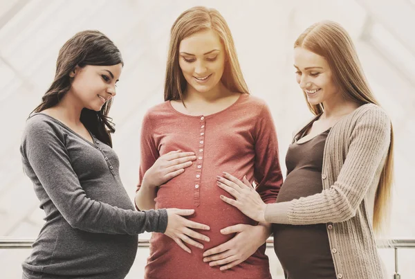 Two cheerful women touching their pregnant friend — Stock Photo, Image