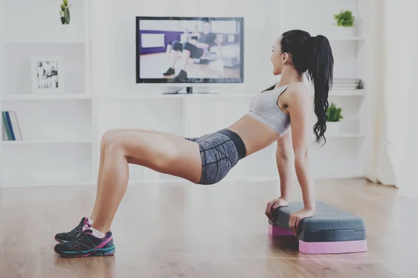 Kvinnan gör fitness hemma på vardagsrumsgolvet — Stockfoto