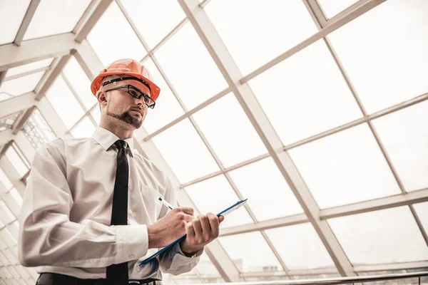 Joven arquitecto serio en casco en oficina — Foto de Stock