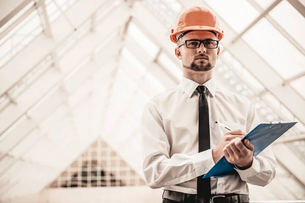 Joven arquitecto serio en casco en oficina — Foto de Stock