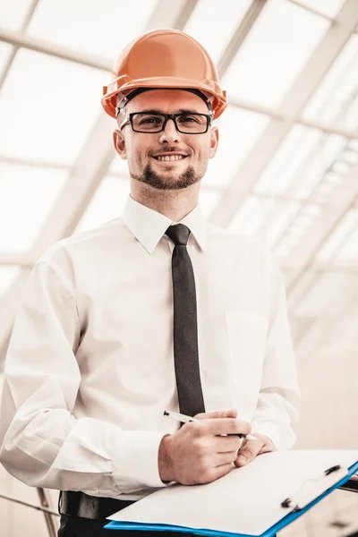 Jovem arquiteto sorridente no capacete no escritório — Fotografia de Stock