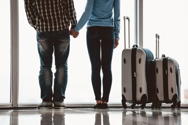 Couple holds hands near suitcase in airport — Stock Photo, Image