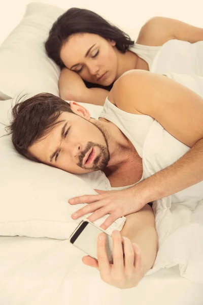 Um homem barbudo branco parece surpreso com o telefone — Fotografia de Stock