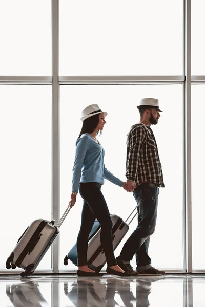 Casal branco de mãos dadas com mala no aeroporto — Fotografia de Stock