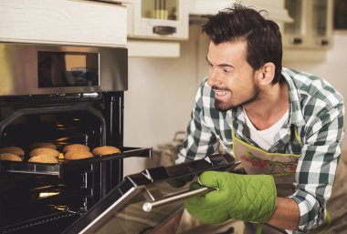 Evde mutfak bakes tepsi tutarak gülümseyen adam portresi.