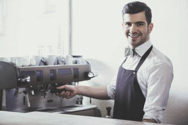 Yakışıklı genç barista kahve dükkanında kahve yapıyor gülümseyen.