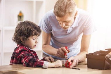 Küçük bebek torunum ve onun dedesi tornavida ile çalışır.