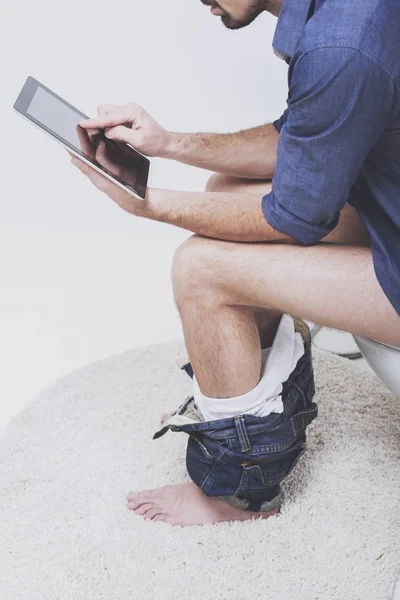 Junger Mann benutzt Tablet auf Toilette. — Stockfoto