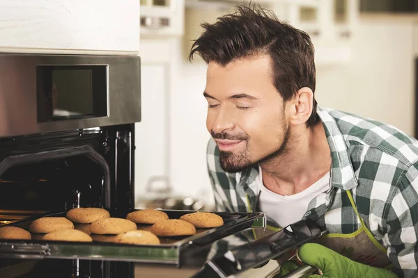 Uśmiechnięty mężczyzna wąchania ciasteczka. — Zdjęcie stockowe