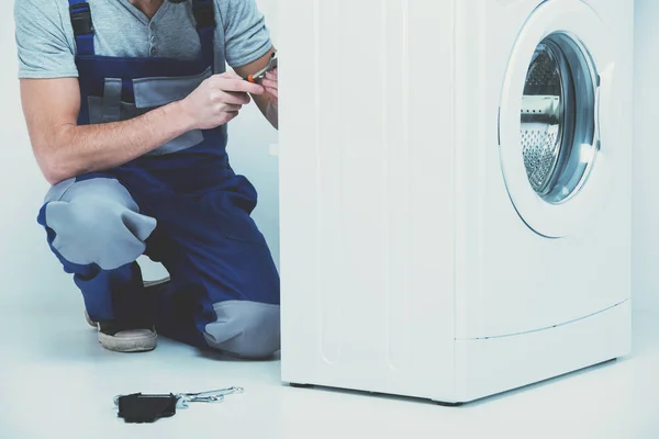 Homem está reparando máquina de lavar roupa . — Fotografia de Stock