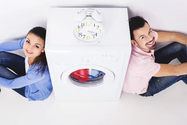 Casal jovem olhando para cima perto da máquina de lavar roupa . — Fotografia de Stock