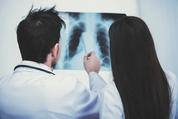 Deux jeunes médecins beaux regardent roentgen dans le bureau médical . — Photo