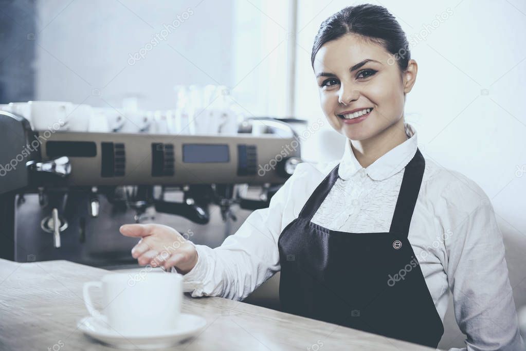 Barista woman offers cappuccino in cafe.