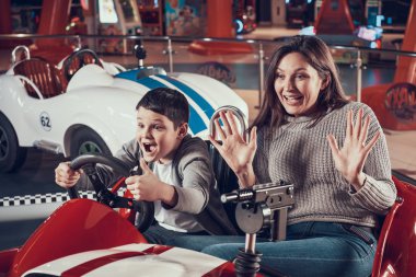 Mutlu anne ve oğlu oyuncak araba üzerinde oturuyor. Aile ile birlikte tatil geçirmek. Eğlence Merkezi, Alışveriş Merkezi, eğlence parkı. Aile dinlenme, eğlence kavramı.