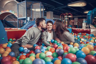 Mutlu bir aile havuzu topları ile oturuyor. Anne çocuk öpüşme. Aile dinlenme, eğlence. Birlikte tatil geçirmek. Eğlence Merkezi, Alışveriş Merkezi, eğlence parkı.
