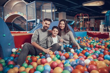 Mutlu aile havuzu topları ile oturuyor. Aile dinlenme, eğlence. Birlikte tatil geçirmek. Eğlence Merkezi, Alışveriş Merkezi, eğlence parkı.
