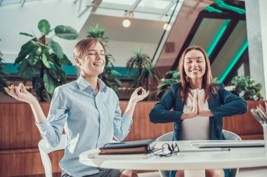 İki işçi kadın ofiste meditasyon.