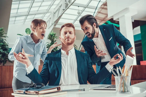 La gente le grita a un trabajador meditante en la oficina . — Foto de Stock