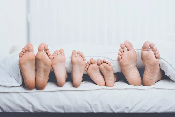 De cerca Familia en la cama bajo cubierta Mostrando Pies — Foto de Stock