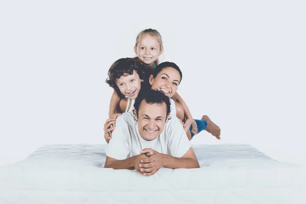 Linda familia sonriente que miente en el colchón ortopédico — Foto de Stock