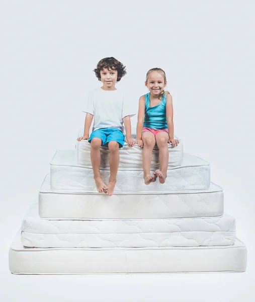 Menina e menino sentados no topo da pirâmide do colchão — Fotografia de Stock