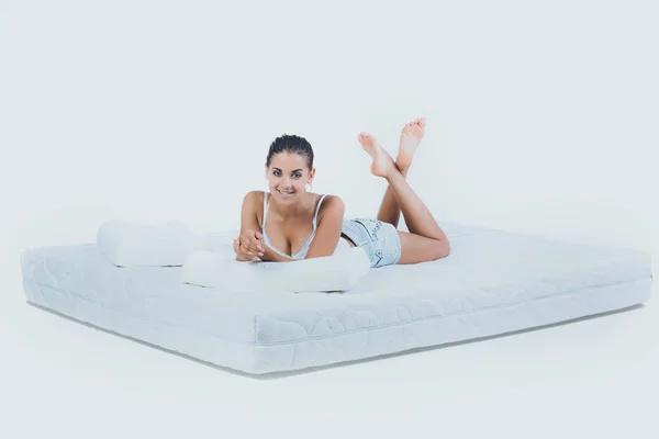 Ortopedik yatak üzerinde yatan genç gülümseyen kadın — Stok fotoğraf