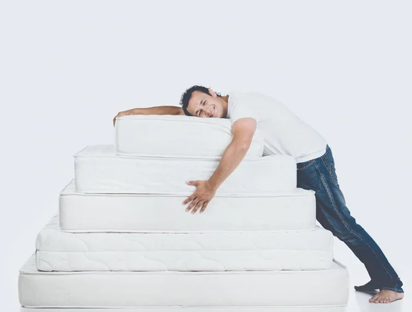 Smiling Man Lying on Pyramid of Mattress Stock Photo