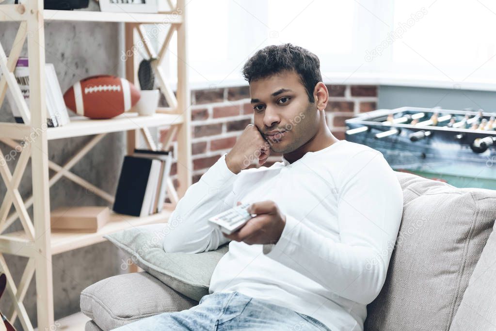 Indian Man Sitting on Sofa with Remote Control.