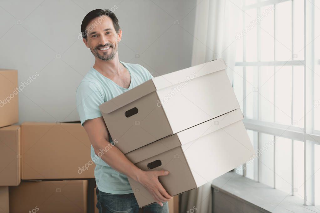 Young Bearded Guy with Cardboard Boxes in Hands.