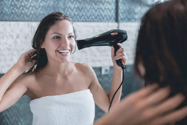 Mladá dívka vysouší vlasy Fén po sprchování . — Stock fotografie