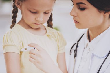 Genç kadın çocuk doktoru derece ölçme.