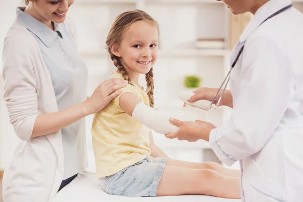 Lekarz przewija strony małe dziewczynki z bandażem. — Zdjęcie stockowe