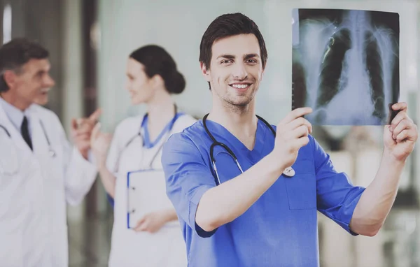 Chirurgul zâmbitor examinează cu atenție scanarea cu raze X . — Fotografie, imagine de stoc