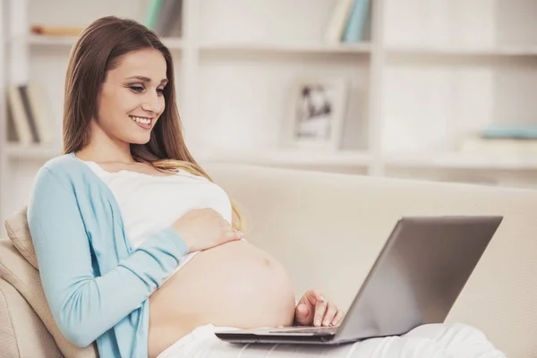 Gravid flicka med nakna mage använder Laptop. — Stockfoto