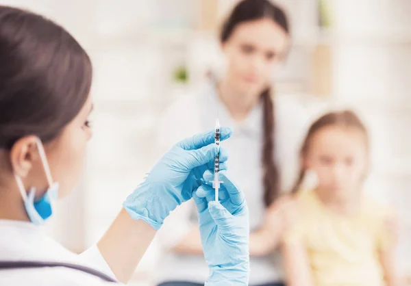 Лікар в масці підготувати вакцинації для маленької дівчинки — стокове фото