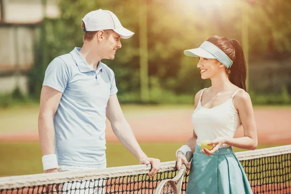 Jovem par de jogadores de tênis se comunica no tribunal — Fotografia de Stock