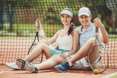 Mutlu çifti raketleri ile oturuyor tenis oyuncuları
