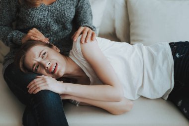 Bacaklar anne kanepede yatan genç kızı üzgün. Aile ilişkisi var. Endişeli anne. Psikolojik yardım. Mutsuz kız. Kavramı destekler. Korkmuş kişi. Kadınlar beyaz kanepe.