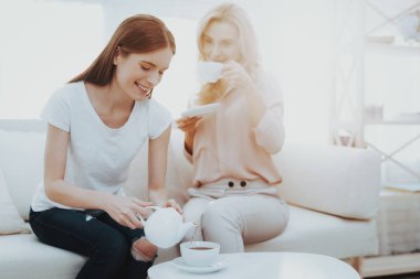 Anne ve kızı koltukta çay içme otururken. İnsanlar iyi ruh hali. Anne-baba ve çocuk arasındaki iletişim. Mutlu anne ve kızı. Sabah kahve. Beyaz koltuk üzerinde gülümseyen kadın.