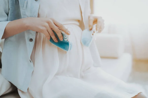 Закрывай. Беременная женщина держит обувь для новорожденного . — стоковое фото
