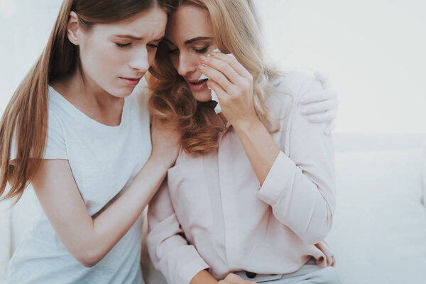 Woman Comforts Unhappy Teenage Daughter at Home. Sitting at Home on Couch. Girl with Problem. Conflict in Family. Parent and Child. Unhappy Girl. Communication Concept. Relationship Concept.