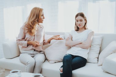 Anne ve kızı beyaz odada arasında kavga. Duygusal tartışma. Kanepede oturan. Aile çatışmada. Üst ve alt. Mutsuz kız. İletişim kavramı. İlişkimde sorunlar.
