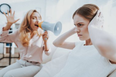 Anne ve kızı beyaz odada arasında kavga. Duygusal tartışma. Kanepede oturan. Aile çatışmada. Üst ve alt. Mutsuz kız. İletişim kavramı. İlişkimde sorunlar.